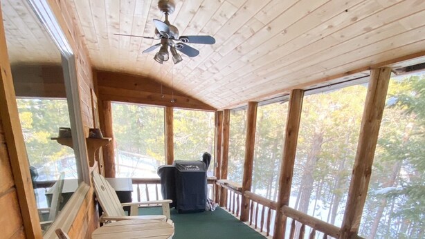 Une terrasse en bois avec un ventilateur de plafond, une table et des chaises.