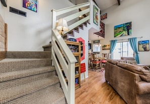 Una escalera que conduce a un segundo piso, un comedor con mesa y sillas, y una sala de estar con sofá y lámpara.