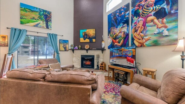 A living room with a fireplace, comfortable seating, and various artworks on the walls.