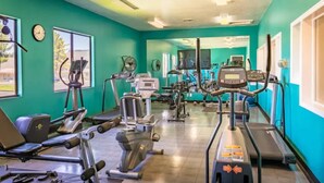 Un gimnasio con diversas máquinas de cardio, una cinta de correr y una máquina de remo.