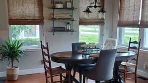 Een eetgedeelte met een ronde tafel, vier stoelen, een potplant en een hanglamp.