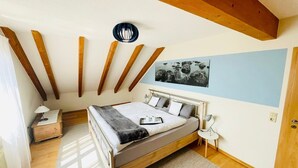 A bedroom with a bed, bedside table, lamp, and a painting on the wall.