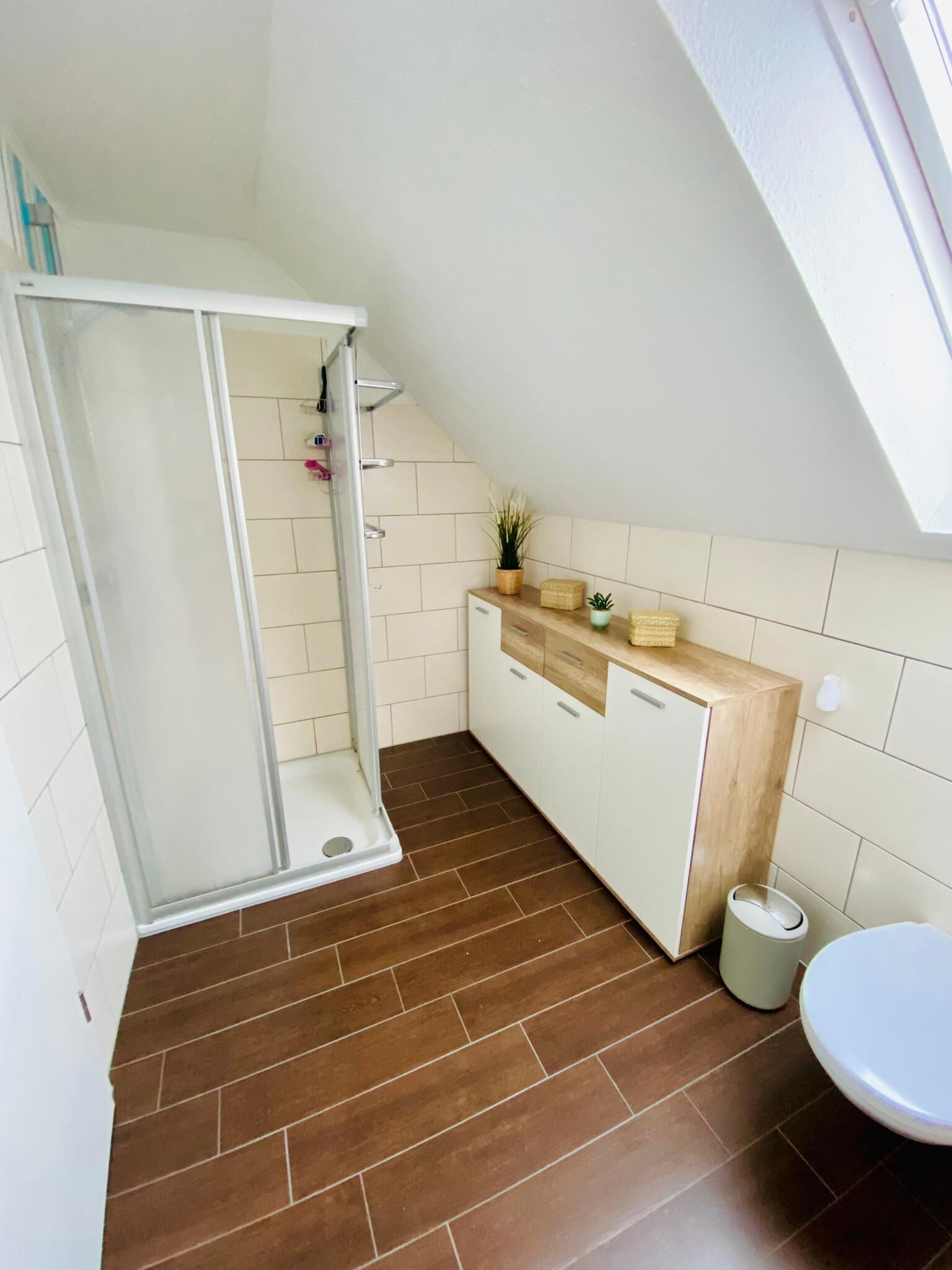 A modern bathroom with a shower, toilet, and a small sink area.