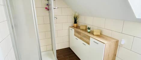 A modern bathroom with a shower, toilet, and a small sink area.