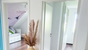 Un intérieur moderne avec un plancher en bois, une porte blanche et un mur blanc agrémenté d’un plafond décoratif.