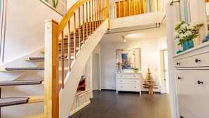 Un escalier avec des rampes en bois et un mur blanc orné d’un tableau.