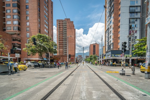 Una calle con tranvías, edificios altos y cielo despejado.