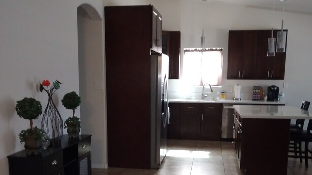A modern kitchen with dark wooden cabinets, a stainless steel refrigerator, and a central island. - Close to shopping and freeway access.  (Yuma)