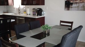 A dining area with a glass-top table, dark wooden chairs, and a modern pendant light. - Close to shopping and freeway access.  (Yuma)