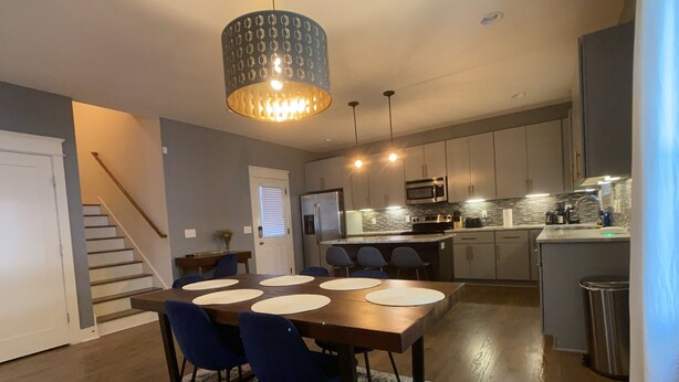 A modern kitchen with a central island, built-in appliances, and a dining area with a table and chairs. - The Nations Home Close to Downtown (Nashville)