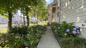 A residential street with a sidewalk lined with hydrangea bushes and a row of houses with a common architectural style. - The Nations Home Close to Downtown (Nashville)
