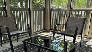 A covered patio area with a pool table, two chairs, and a small table. - The Nations Home Close to Downtown (Nashville)