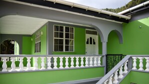 Un immeuble à plusieurs étages, aux murs extérieurs verts et blancs, avec des rampes blanches et un escalier.