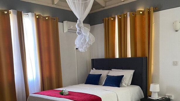 Une chambre à coucher avec un lit, une table de chevet, une lampe suspendue et des rideaux.