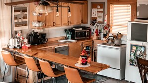 A kitchen with wooden cabinets, a central island with bar stools, a microwave, a stove, and a refrigerator.