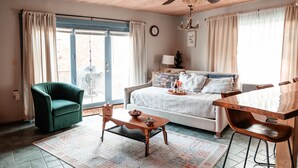 A cozy living room with a sofa, a coffee table, a dining table, and a ceiling fan.