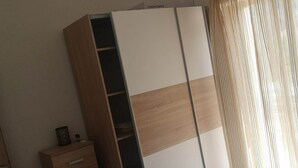 Une armoire à l’extérieur en bois et à l’intérieur blanc, dotée de plusieurs compartiments et d’une section pour suspendre les vêtements.
