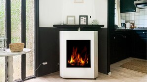 Una cocina moderna con chimenea empotrada, una mesita con un tazón y una ventana con cortinas de encaje.