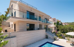A modern two-story house with a swimming pool, outdoor seating, and a staircase leading to a balcony. - Gorgeous apartment in Selca with house sea view (Selca)