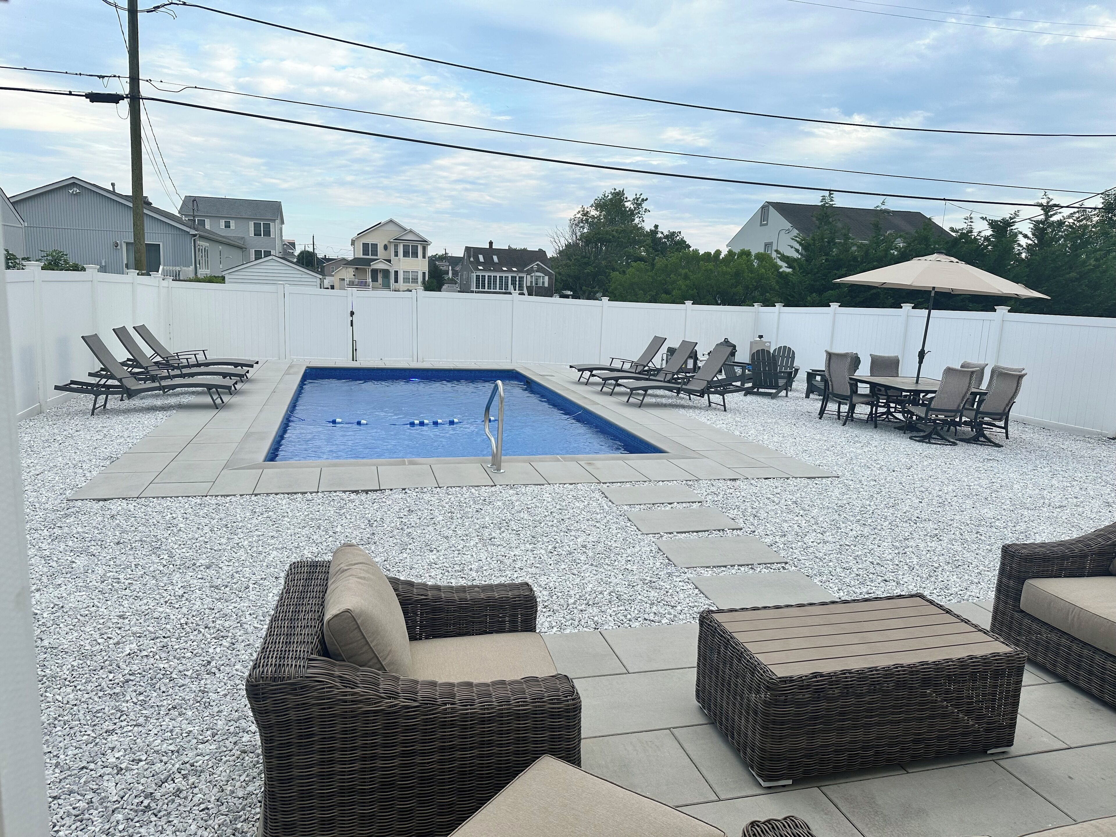 Un patio trasero con piscina, sillas de descanso y mobiliario exterior.