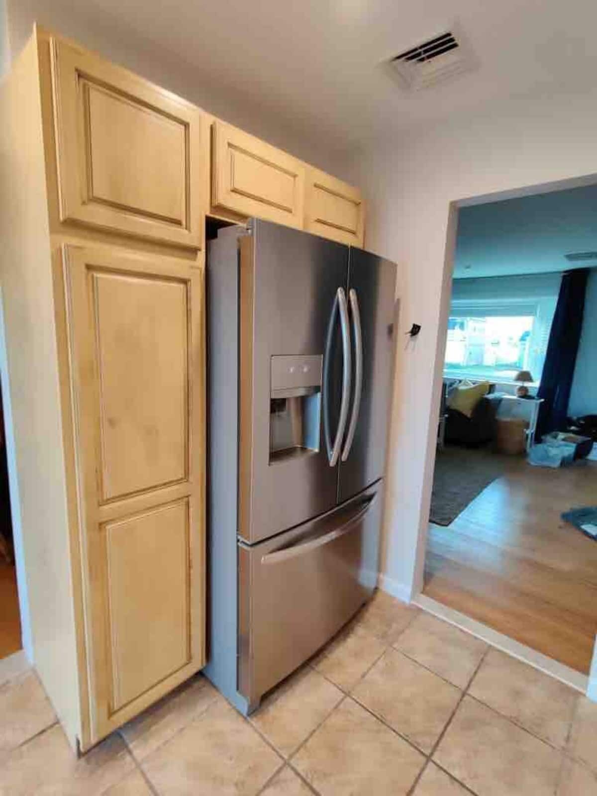 A kitchen with wooden cabinets, a stainless steel refrigerator, and a built-in oven.