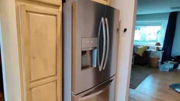 A kitchen with wooden cabinets, a stainless steel refrigerator, and a built-in oven.