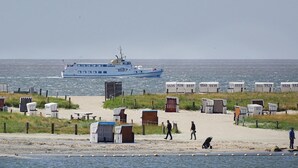 A beach with a boat, beach huts, and a sandy path. - Beach front apartment in Büsum with sauna (Büsum)