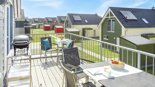 A balcony with outdoor furniture, a grill, and a view of neighboring houses. - Beach front apartment in Büsum with sauna (Büsum)
