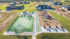 Eine Vogelperspektive auf ein Wohngebiet mit Häusern, einem Spielplatz und einem Sportplatz.