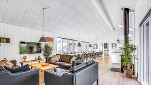 Ein modernes Interieur mit einem langen Essbereich, Ledersofas und einem großen Fernseher.