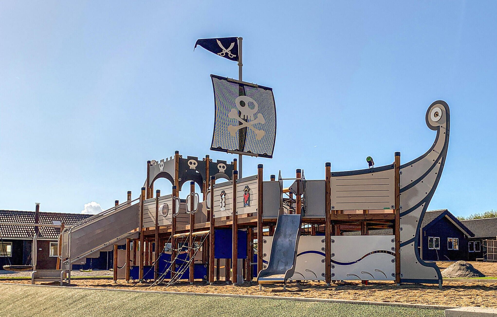 Uma estrutura de recreação com o tema de um navio pirata, incluindo uma bandeira, um escorrega e balanços.