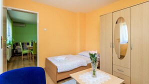 A small room with a bed, a blue chair, a table with a vase of flowers, and a wardrobe.