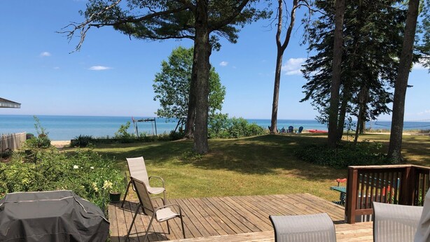 Une terrasse en bois avec des meubles d’extérieur, un barbecue et une vue sur l’océan.