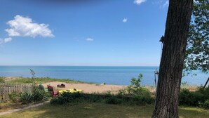 Une vue sur la plage avec une clôture en bois, un arbre et une zone herbeuse.