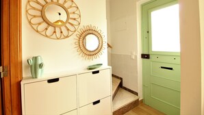 A hallway with a white cabinet, a green door, and two wall-mounted mirrors.
