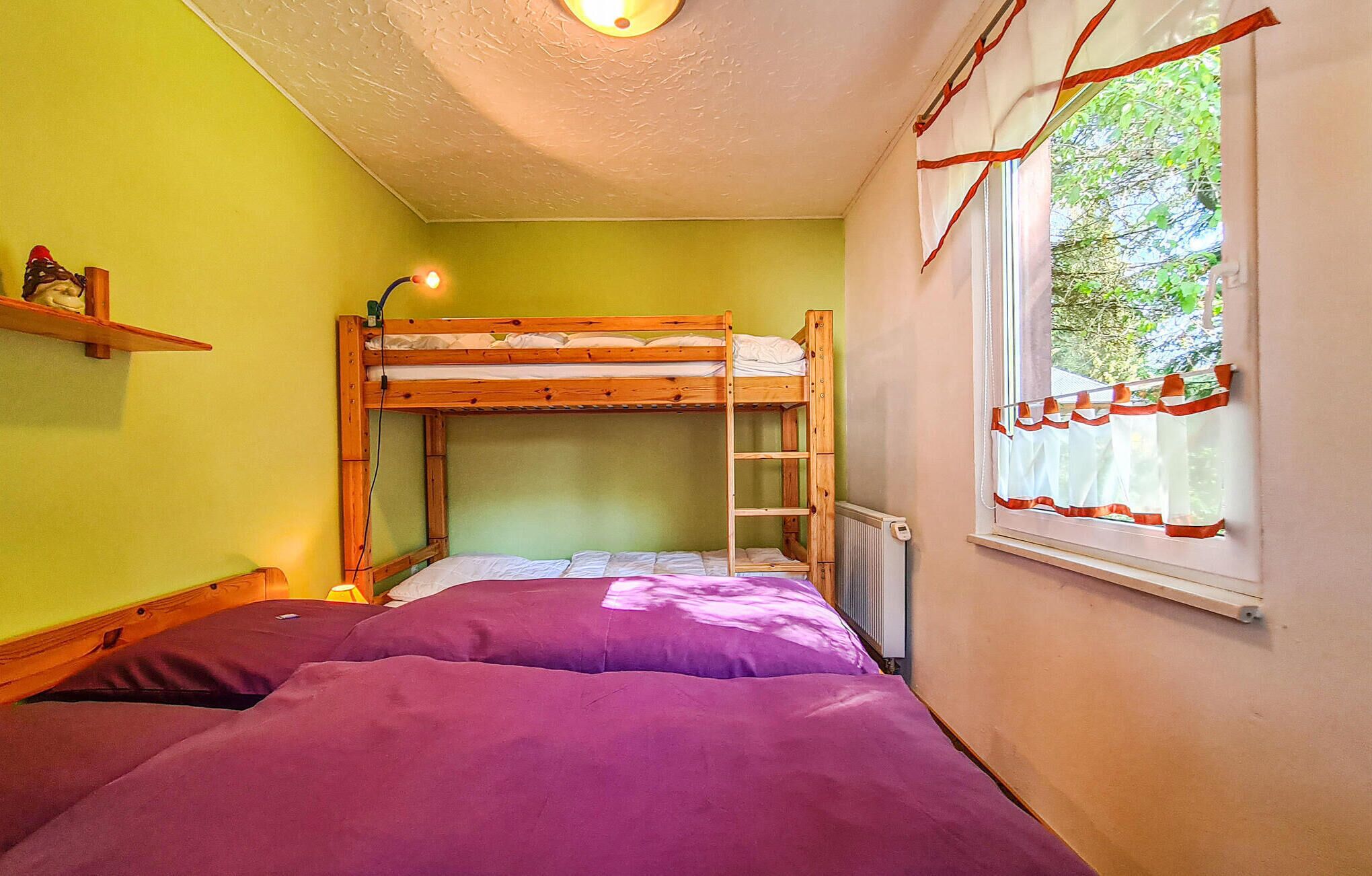 Ein Zimmer mit einem Etagenbett, einem Fenster mit Vorhängen und einem Regal mit Gegenständen.