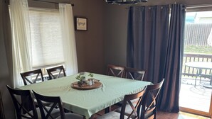 A dining area with a table set for four, wooden chairs, a chandelier, and a view of the outdoors. - Beautiful! (Black Hawk)