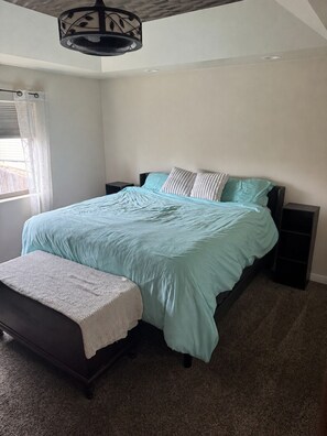 A bedroom with a bed, bedside tables, a bench, and a ceiling fan.