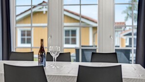 A dining table with a bottle and two glasses, large windows with a view of houses, and a modern interior design. - Beautiful home in Gråsten with WiFi (Gråsten)