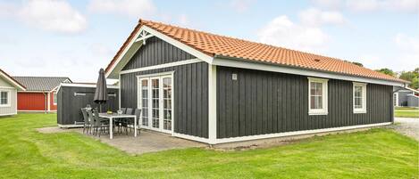 Il s’agit d’un bâtiment d’un seul étage, à l’extérieur sombre, surmonté d’un toit recouvert de tuiles rouges. Il dispose d’un patio avec des sièges et une table à l’extérieur.