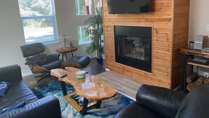 Una sala de estar moderna con chimenea, asientos cómodos y ventanas amplias.