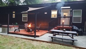 Un patio cubierto con una chimenea, asientos exteriores y una escalera que lleva a una terraza.