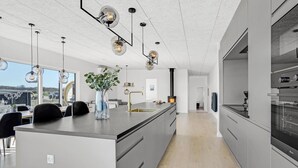 A modern kitchen with a large island, pendant lighting, and a view of the city. - Pet friendly home in Børkop with sauna (Børkop)