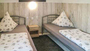 A room with two single beds, each with a floral-patterned bedspread and matching pillows. There is a small wooden nightstand between the beds, and a wall-mounted light fixture above. - 2 bedroom gorgeous apartment in Bandow (Bandow)