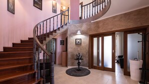 A spacious foyer with a wooden staircase, a round table with a vase, and a large window. - Stunning home in Sumber (Sumber)