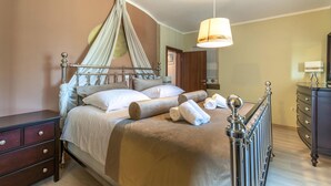 A neatly made bed with a canopy, a bedside table, a dresser, and a hanging lamp. - Stunning home in Sumber (Sumber)