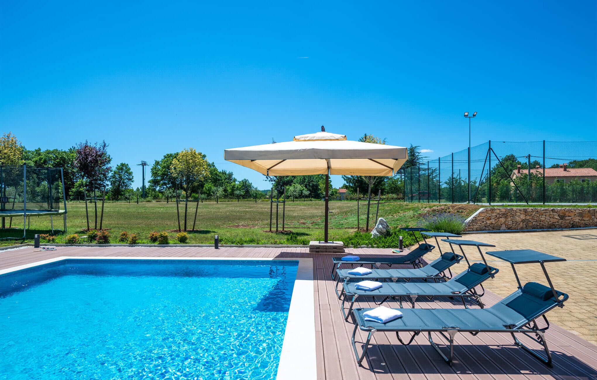 A swimming pool with lounge chairs and an umbrella.