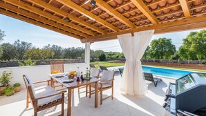 A covered patio with a pool, wooden furniture, and a grill. - Stunning home in Galizana (Galizana)