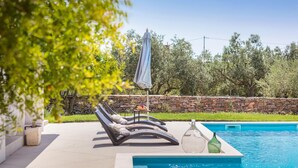 A poolside area with lounge chairs, a stone wall, and a clear blue pool. - Stunning home in Galizana (Galizana)