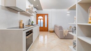 A modern kitchen with a built-in oven, a sink, and a stove. There is a wooden door with glass panels in the background. - Stunning home in Galizana (Galizana)